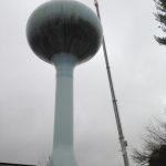 Using our crane with offset jib setting cell antennas on top of water tower.