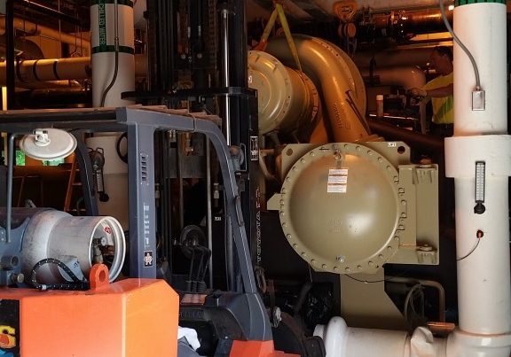 Taking a compressor off a chiller to replace an O-ring. One side is supported by our 10,000 lb. forklift.