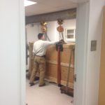 Rigging of optical table using a gantry, chainfalls, beam clamps, nylon straps, and shackles.