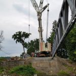 The first truss is tied off and held while the other one is picked. When they are both in place the 90 ton crane reached out and sets the floor beams making it safe to disconnect the 600 ton crane.